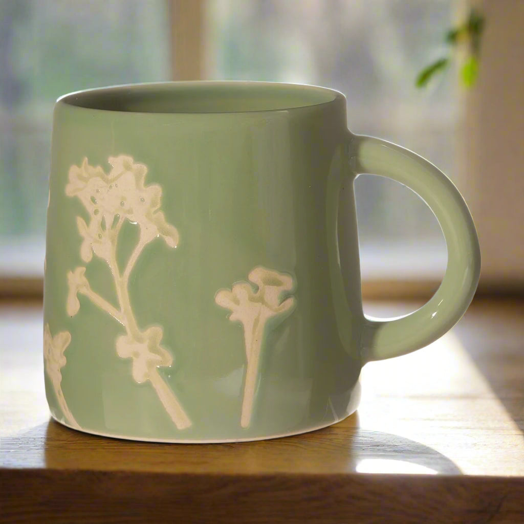 Green mug with floral design on a wooden surface